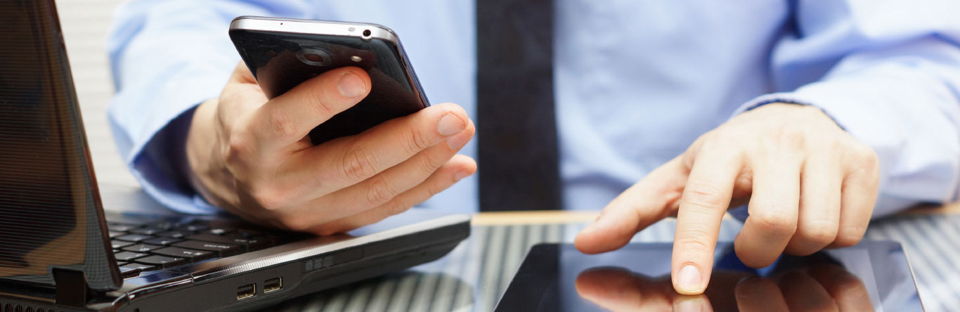 man using cell phone, laptop and tablet